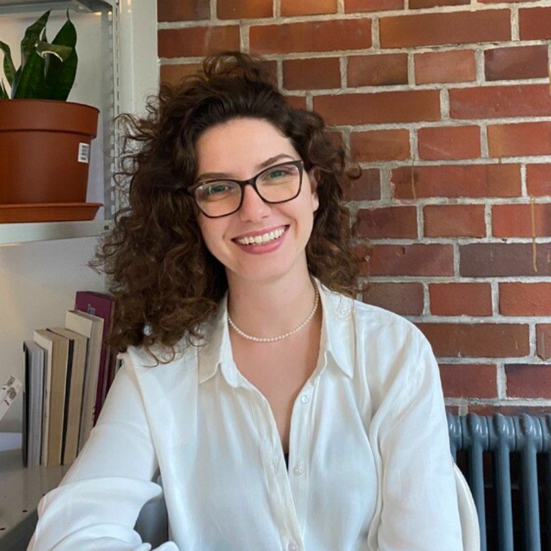 A person receiving a manicure, using a nail brush to clean and shape their nails at a nail salon