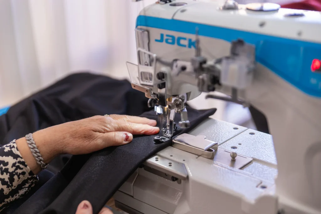 A woman sits in a salon chair, having her nails painted by a nail technician.